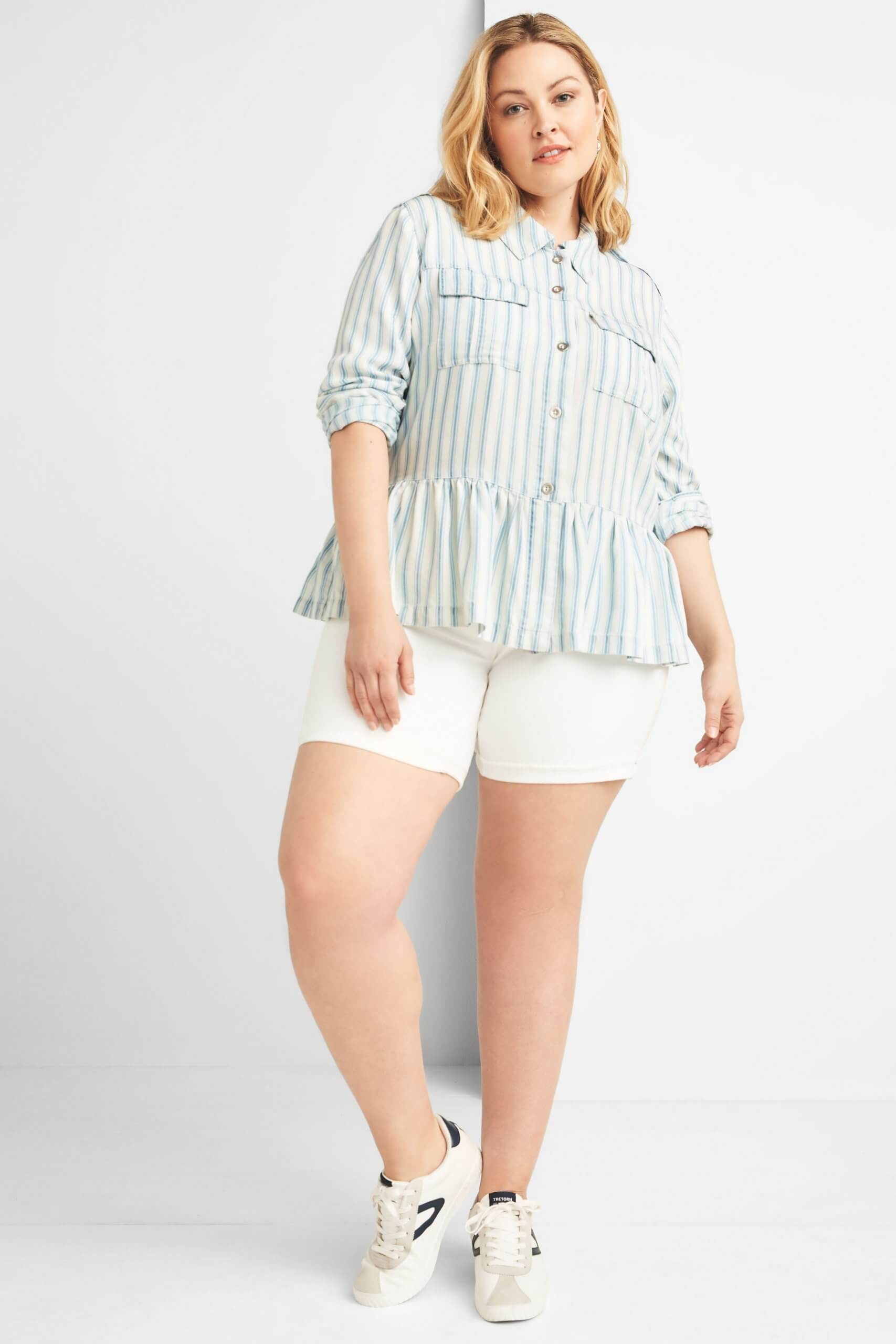 Stitch Fix model wearing plus-size clothing featuring blue and white chambray peplum shirt, white shorts and sneakers.
