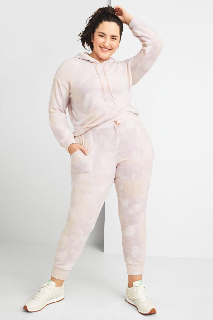 Stitch Fix women’s model wearing matching plus-size pink tie-dye hoodie and joggers with off-white sneakers.