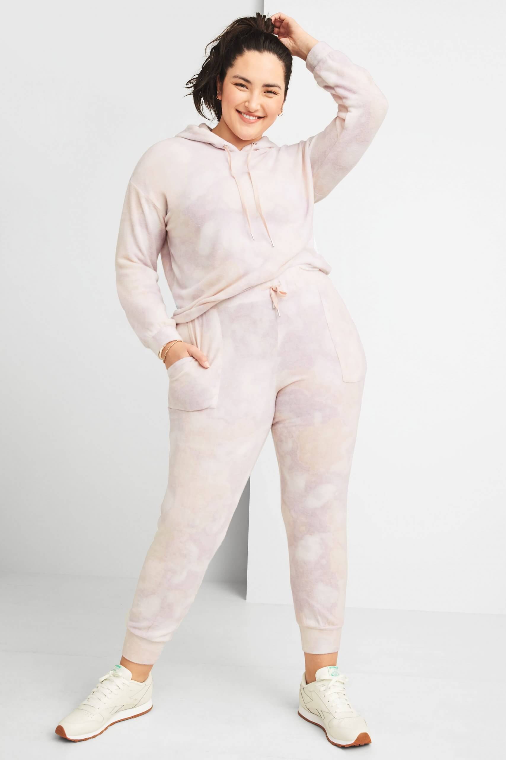 Stitch Fix women’s model wearing matching plus-size pink tie-dye hoodie and joggers with off-white sneakers.