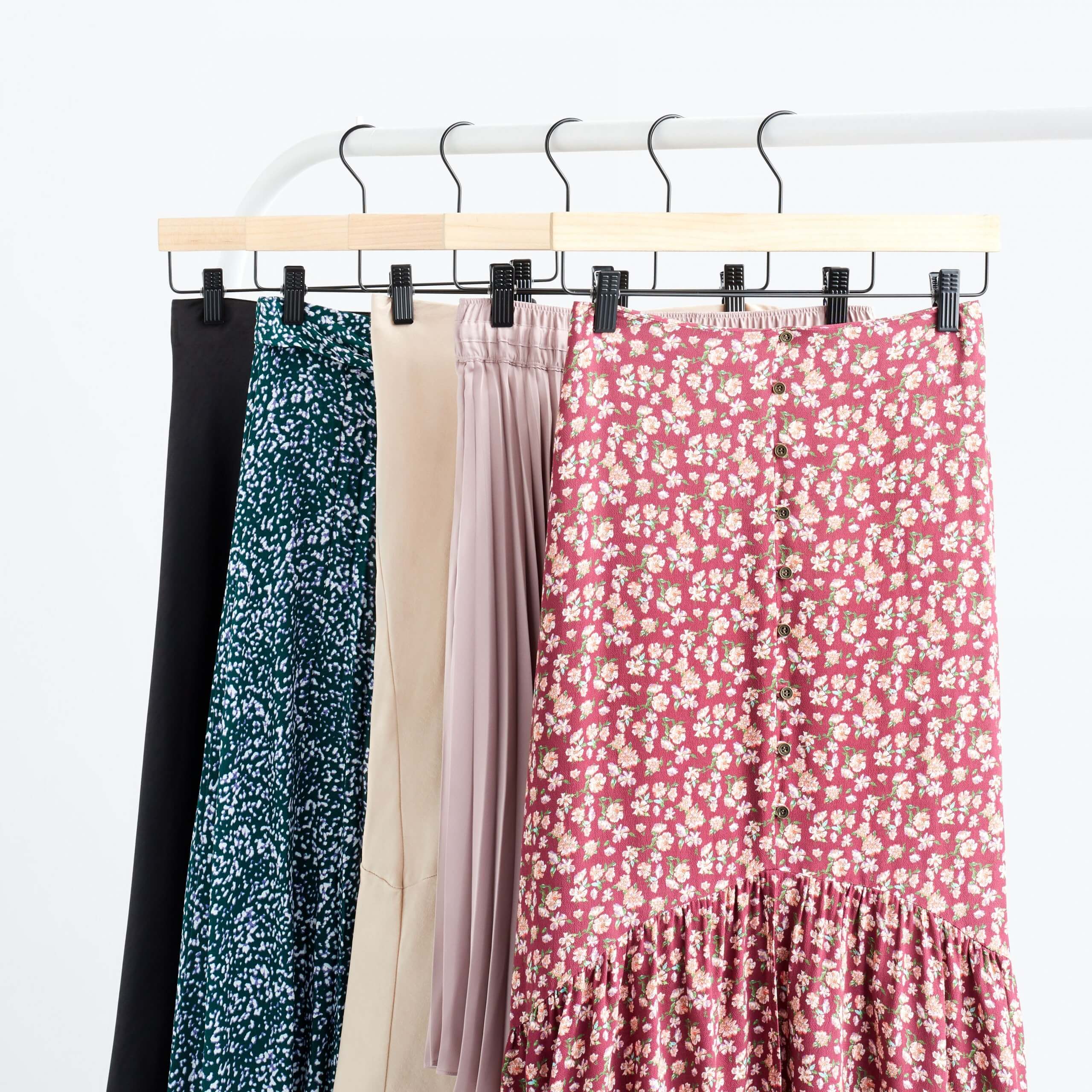 Stitch Fix Women’s rack image of skirts in red floral, blush pink, beige, teal floral and black on wooden hangers. 