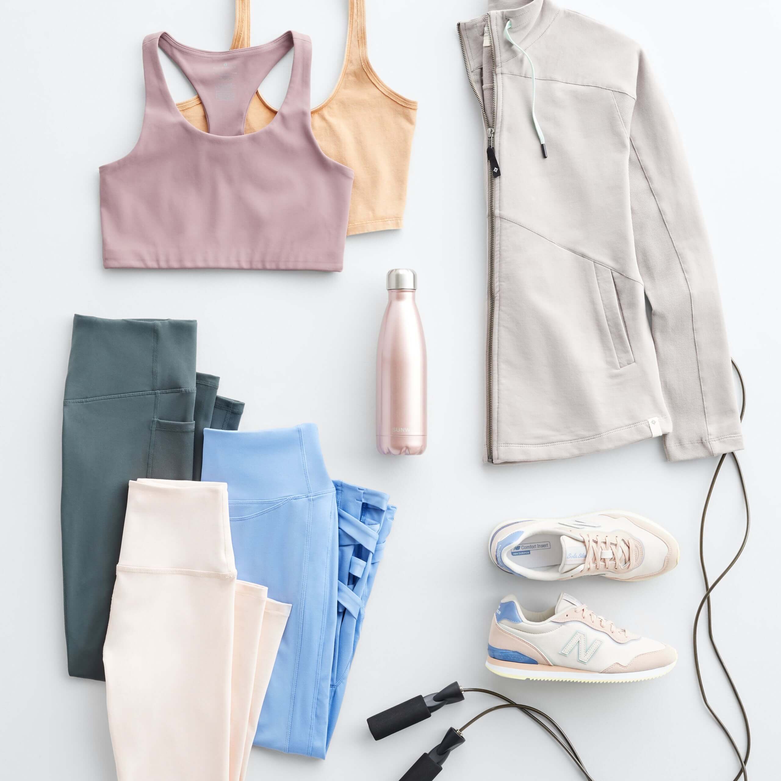 Stitch Fix Women's laydown featuring sports bras in mauve and orange, leggings in grey, light blue and blush, grey active jacket and white sneakers with pink and blue accents. 