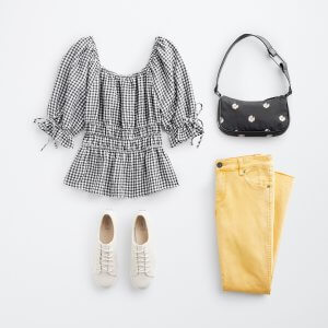 Stitch Fix women’s outfit laydown featuring a puff sleeve black and white striped top, patterned black purse, yellow jeans and white sneakers.