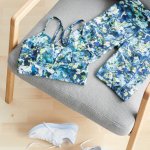 Stitch Fix women’s matching green and blue patterned sports bra and bike shorts laying on grey chair next to white sneakers.