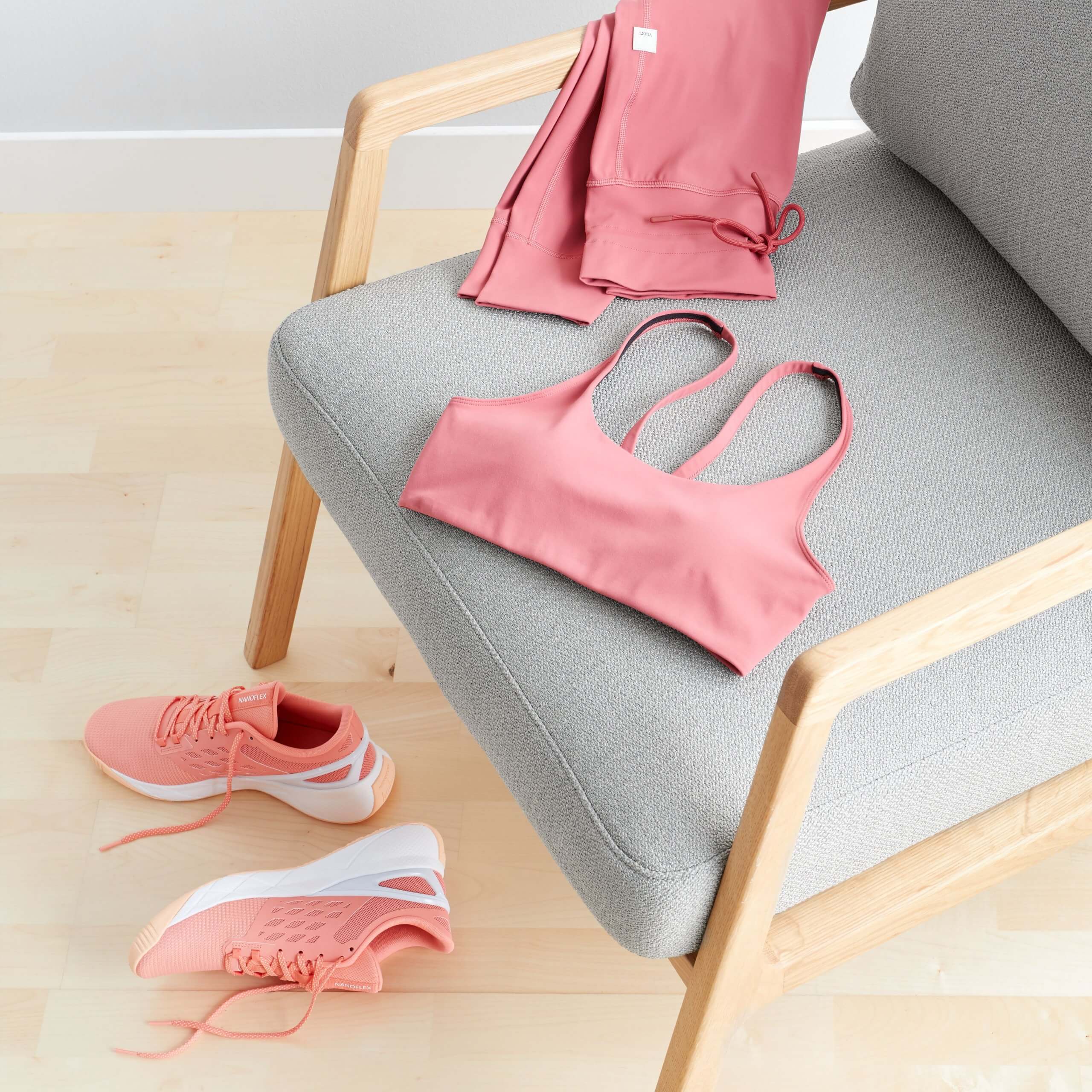 Stitch Fix women’s outfit featuring a pink sports bra and matching leggings draped on chair with coral sneakers on the floor.