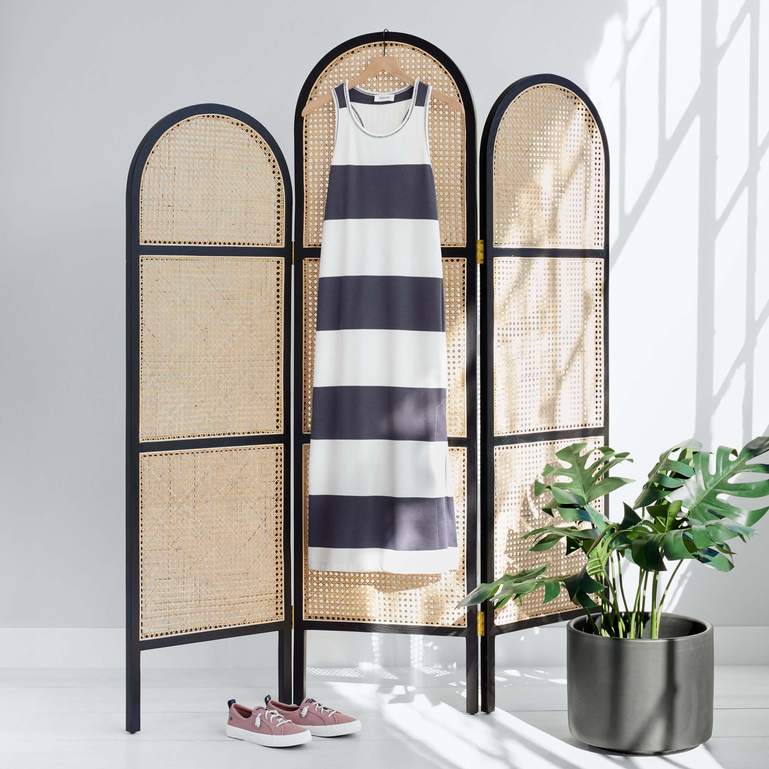 Stitch Fix women’s luxury fabric black and white striped knit maxi dress hanging on dressing screen with purple sneakers next to potted plant.