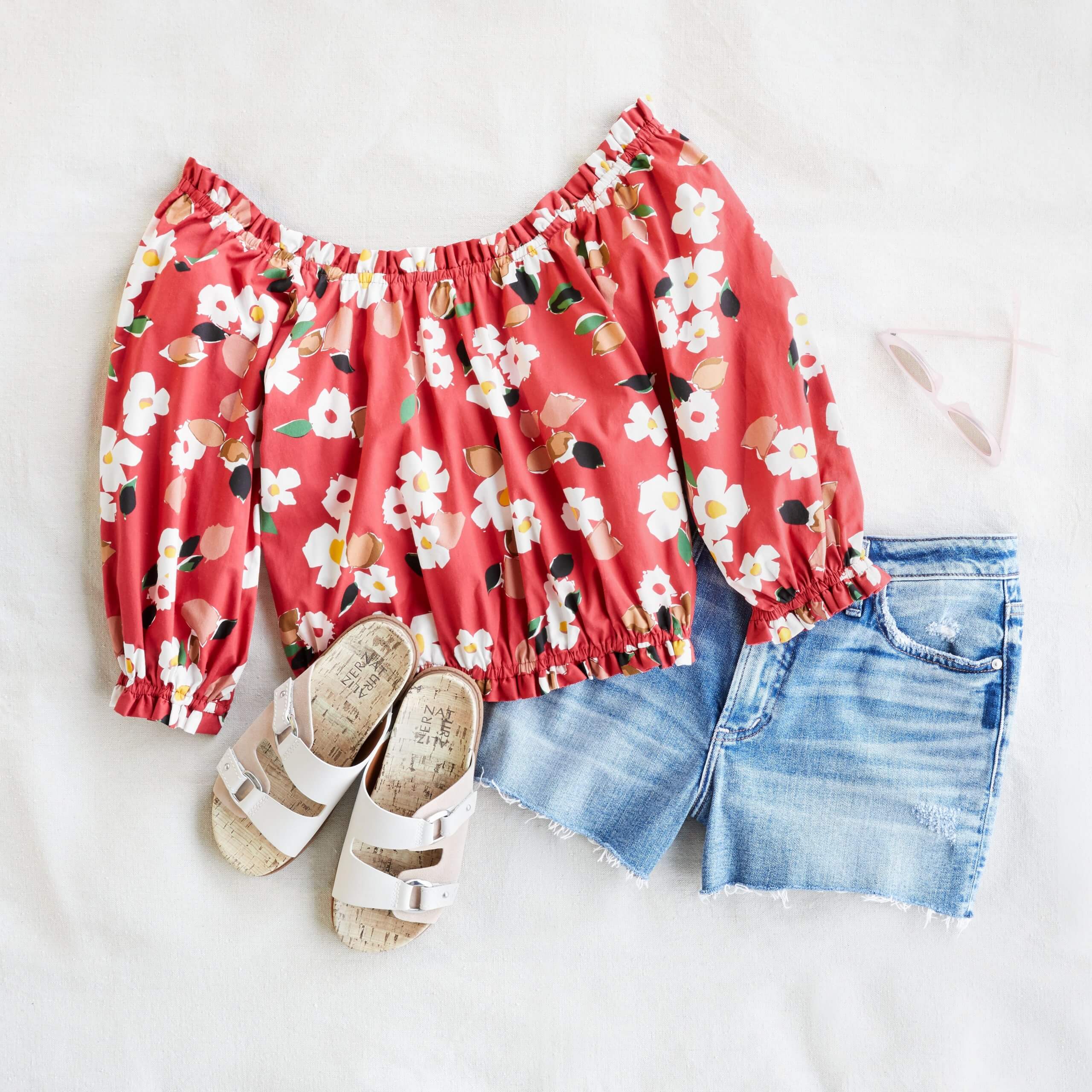 Stitch Fix women's 4th of July outfit laydown featuring blue denim shorts, white sandals, and red and white floral print blouse.
