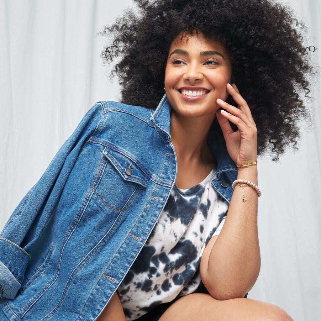 Stitch Fix women’s model in chic style outfit featuring blue and white tie-dye T-shirt and denim jacket.