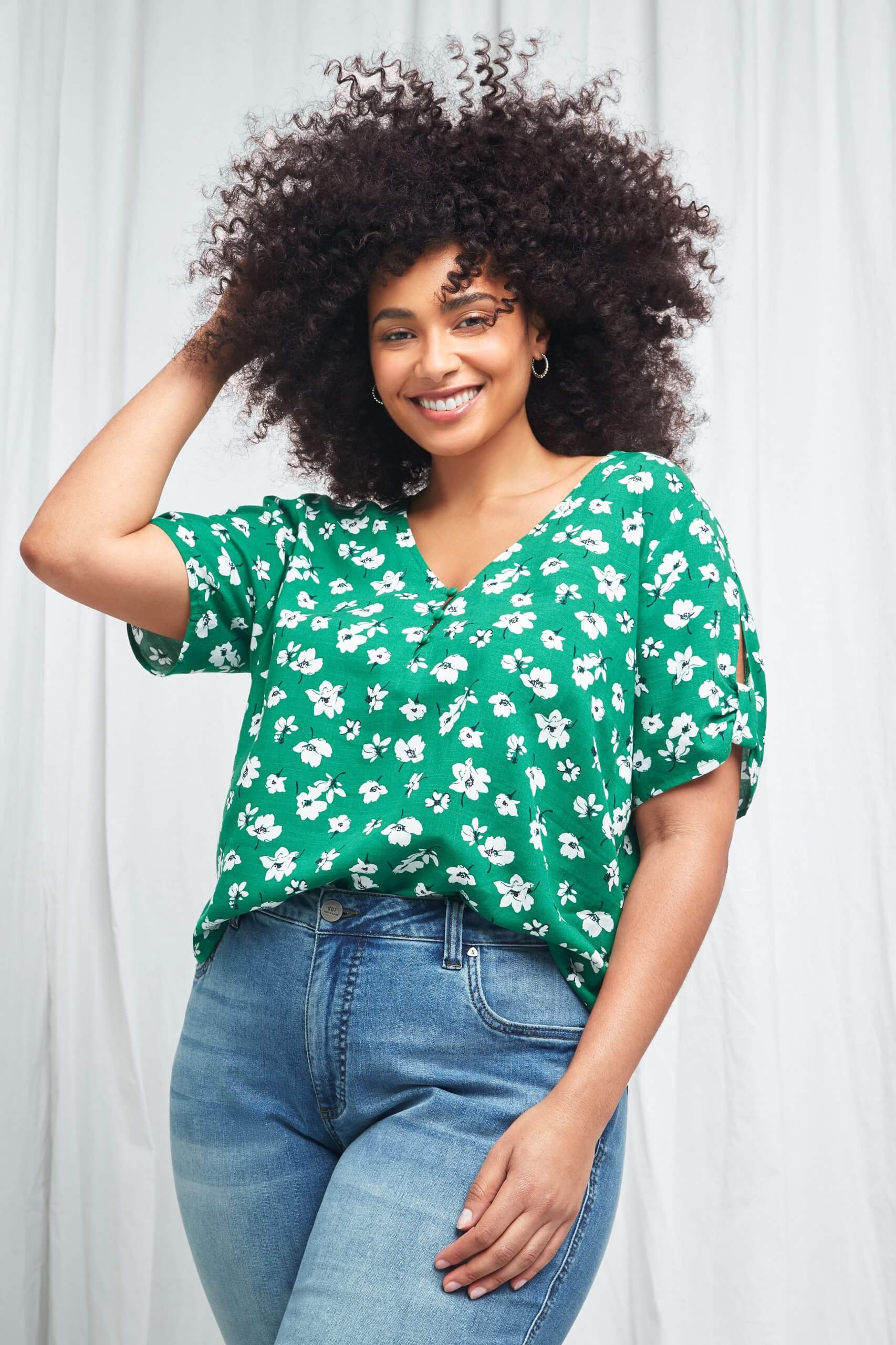 Stitch Fix Women’s model wearing green floral blouse tucked into blue jeans. 