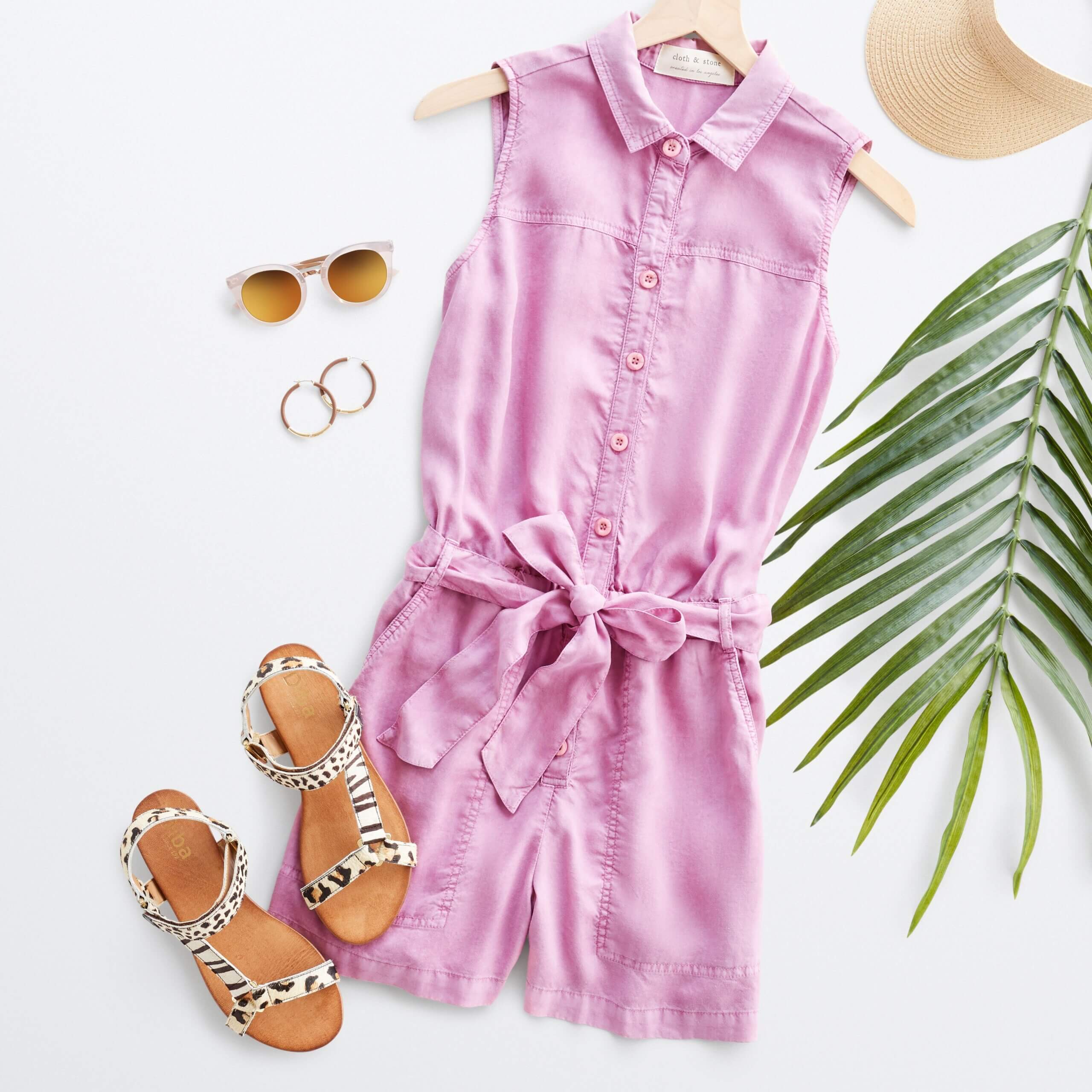 Stitch Fix women's outfit laydown featuring pink collared romper with button-front and tie-waist detail next to brown animal-print sandals and gold hoop earrings. 