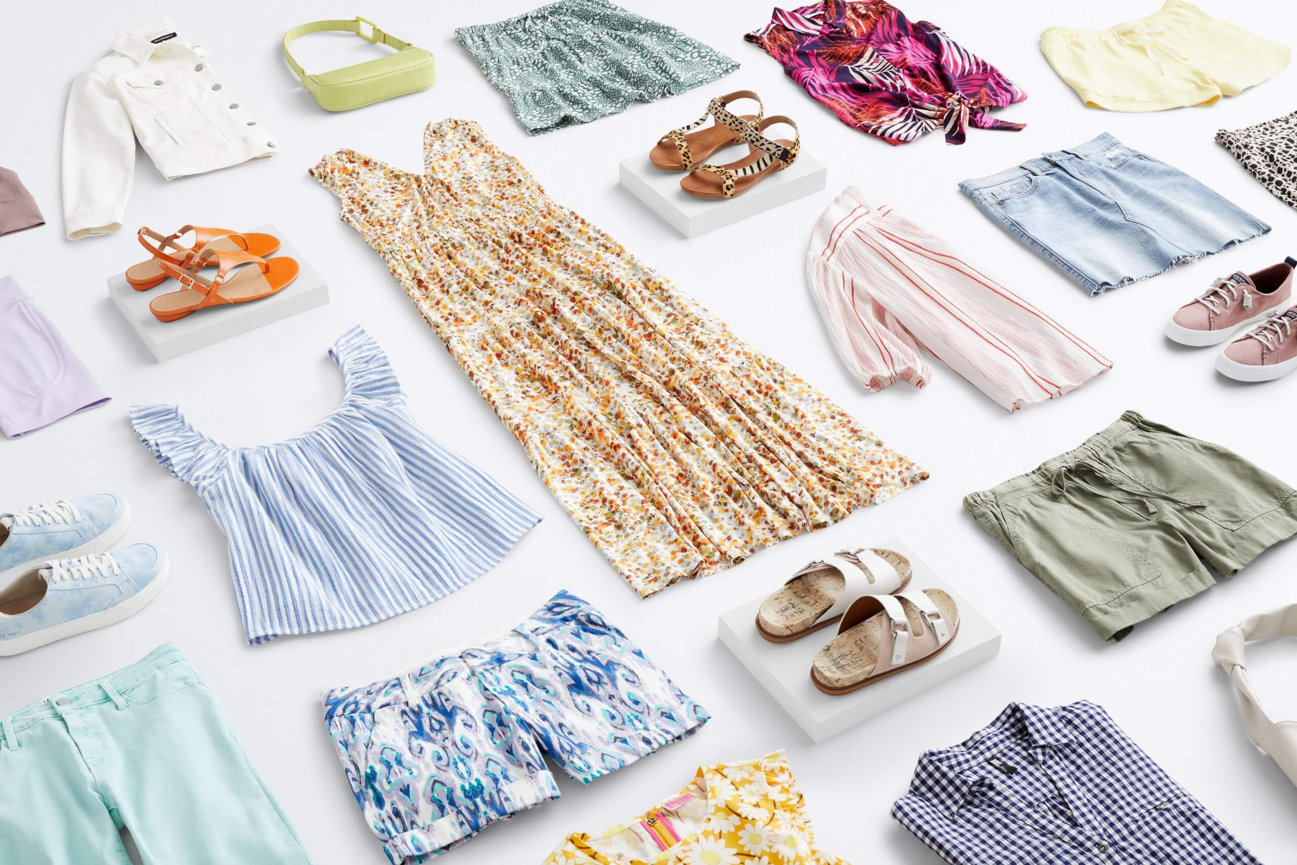 Stitch Fix Women's outfit laydown featuring a wide range of summer pieces including white denim jacket, shorts and skirts in blue, green and yellow tones, printed tank tops, floral maxi dress, sandals and sneakers in various tones.