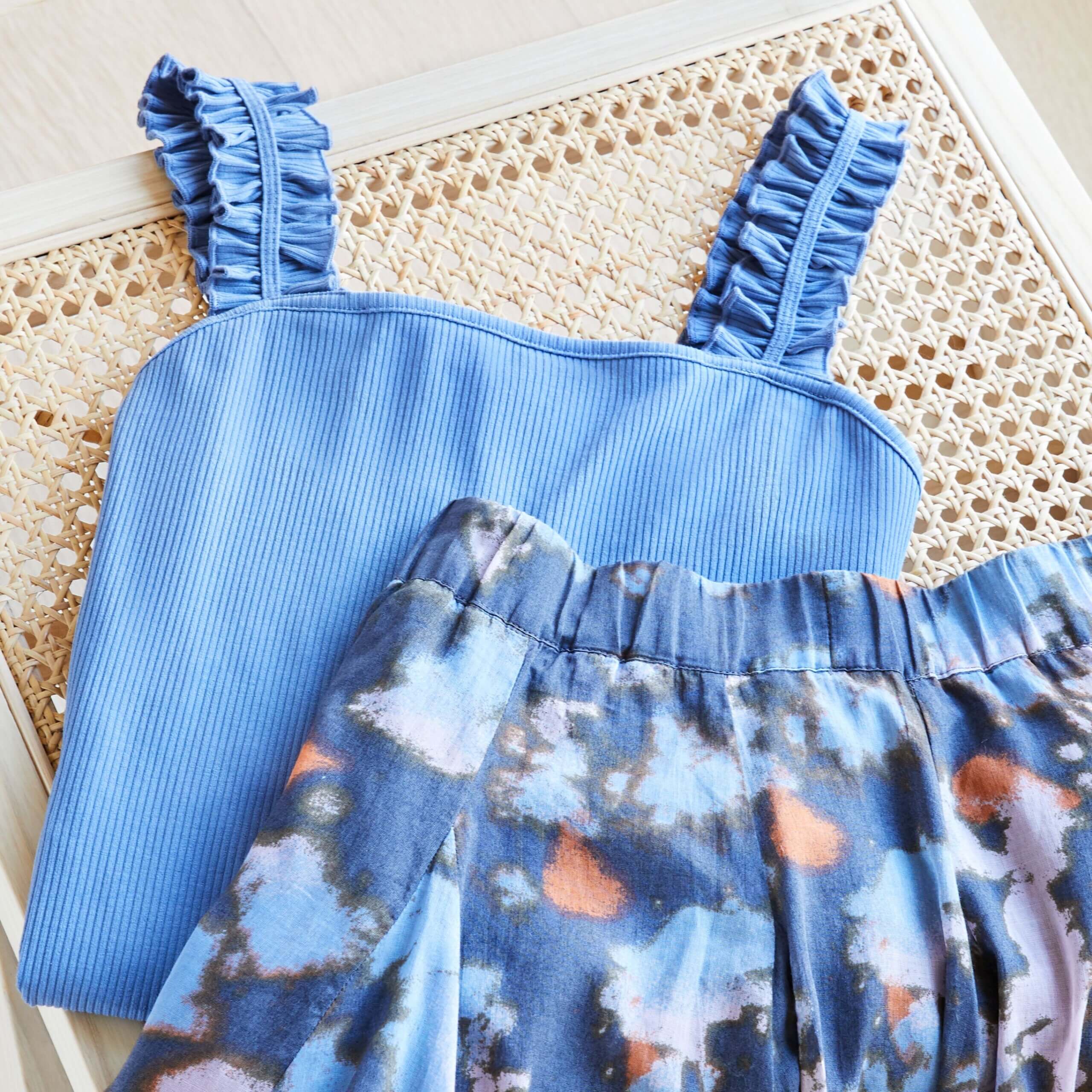 Stitch Fix women’s bodysuit outfit with blue ruffle strap bodysuit and multi-colored abstract print skirt.