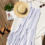 Stitch Fix women’s resort wear blue tiered maxi dress laid down next to sunglasses, straw hat and black slide sandals.