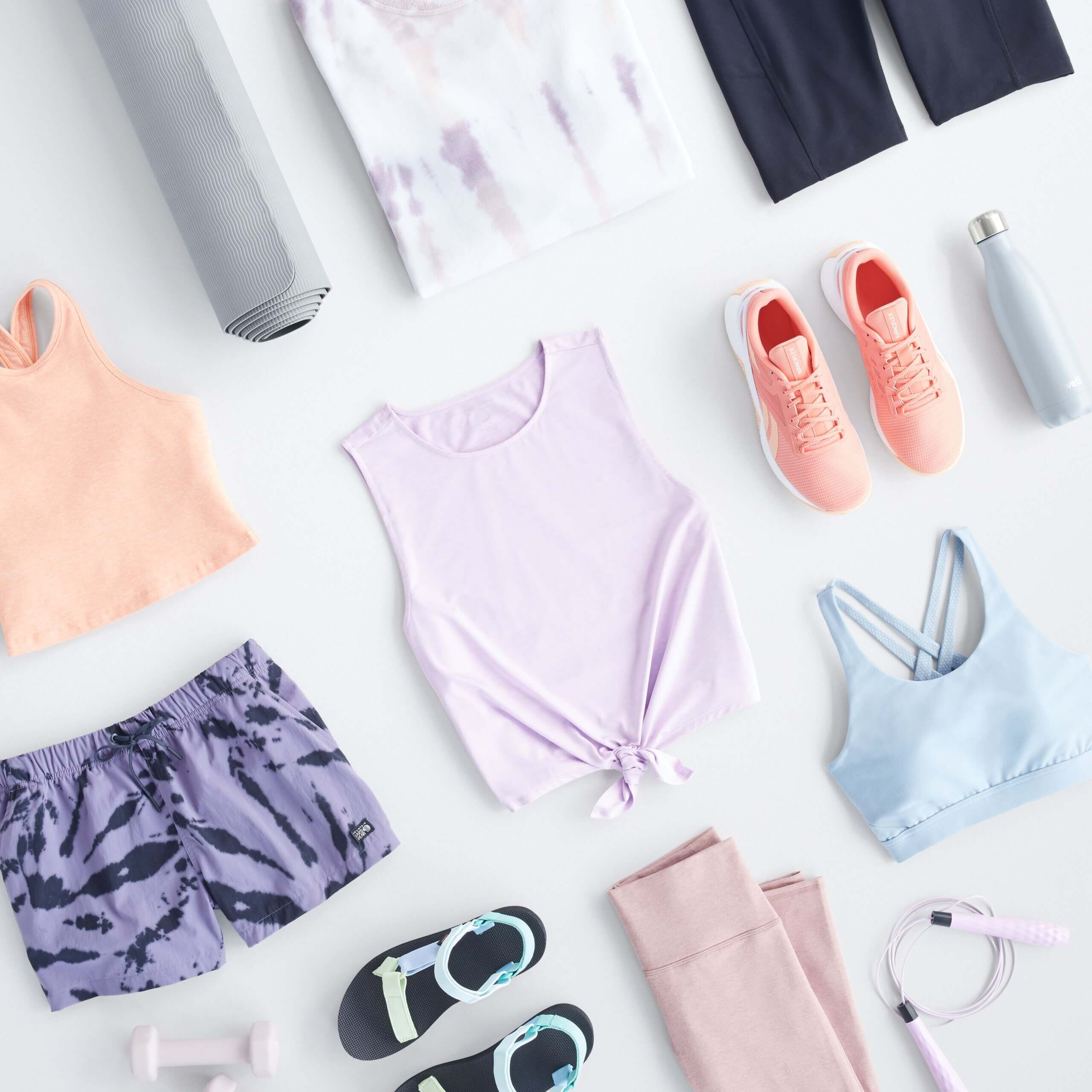 Stitch Fix Women's laydown featuring athletic tops in peach, lilac and baby blue, purple athletic shorts, navy bike shorts, pink sneaker and sandals.