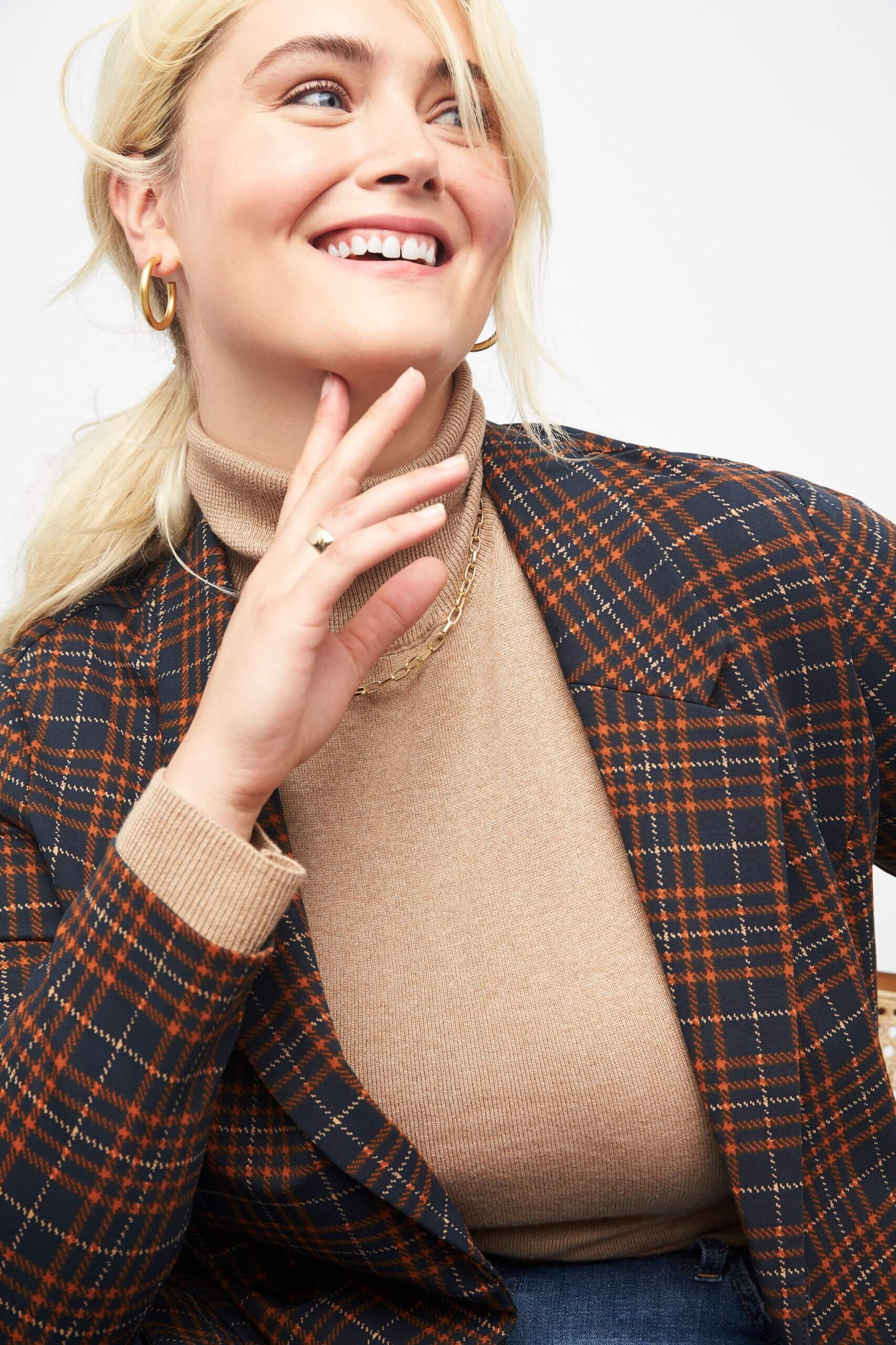 Stitch Fix women’s model wearing thick gold hoop earrings, tan turtleneck and plaid blazer.