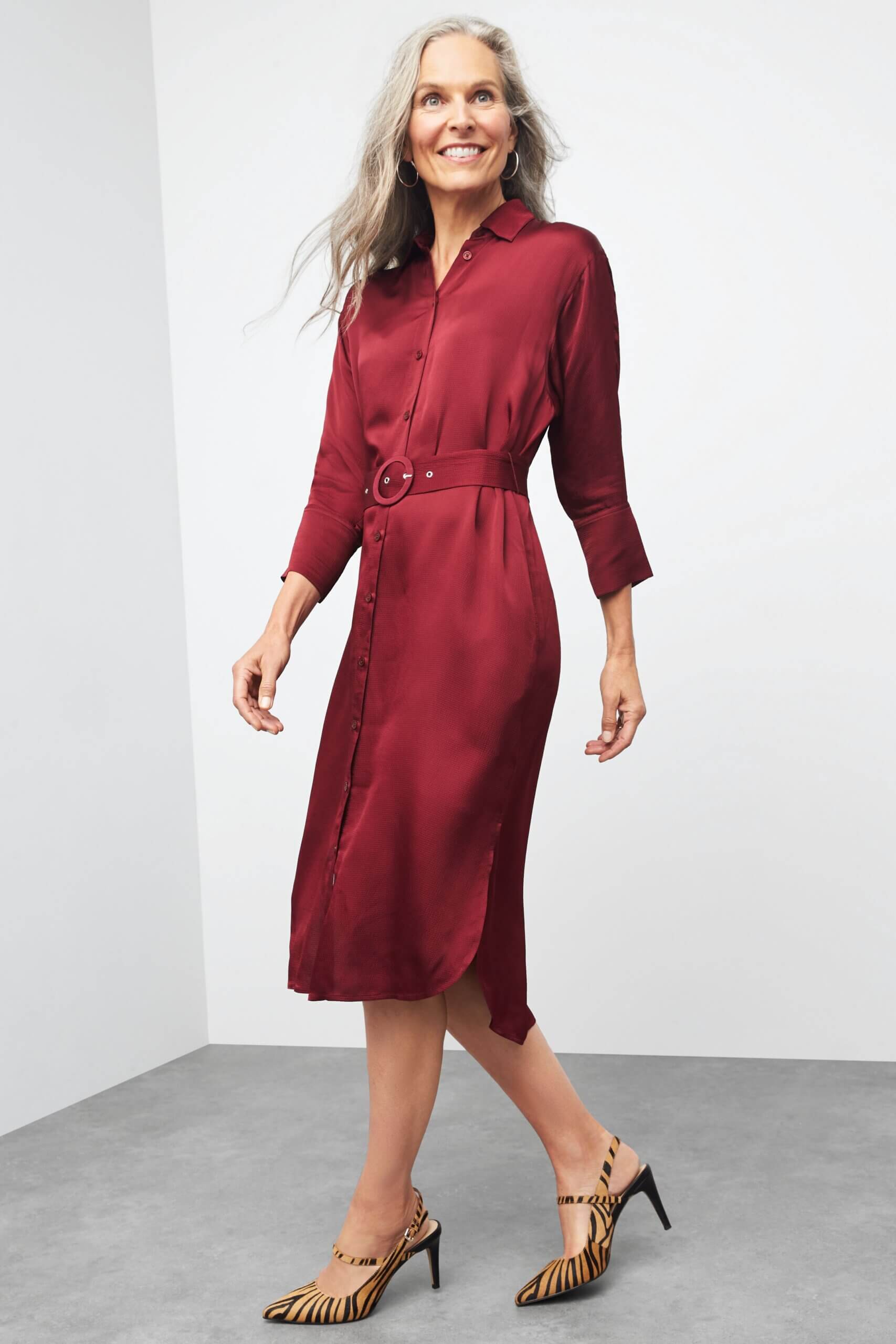 Stitch Fix women’s Christmas outfit on model featuring a burgundy shirt dress with belted waist and tiger print heels.