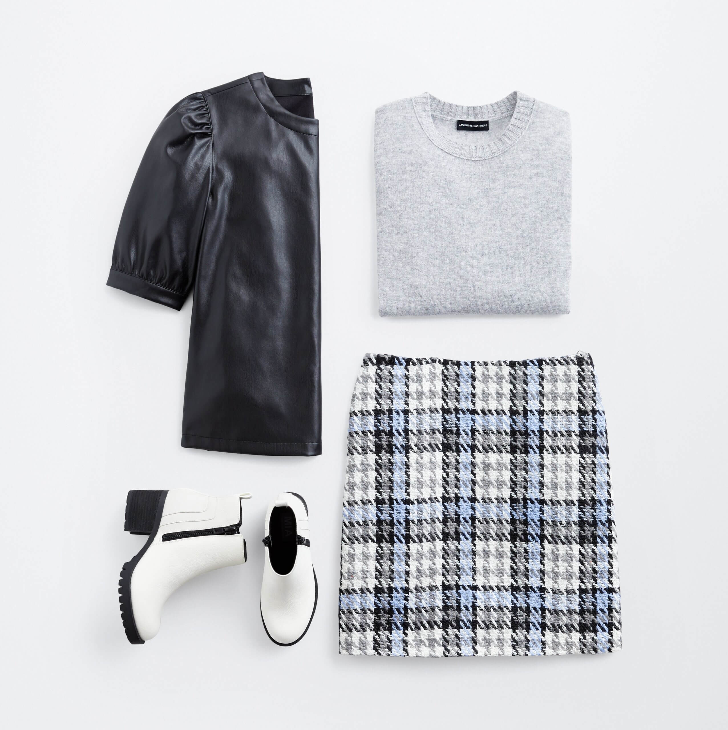 Stitch Fix women’s 2022 fashion trends outfit featuring plaid mini skirt, vegan-leather short sleeve blouse, grey crew neck sweater and white lug-sole ankle boots.