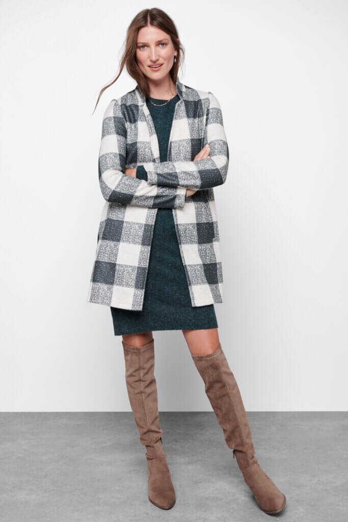 Stitch Fix women's model wearing green dress, black and white checkered cardigan and taupe over-the-knee boots.