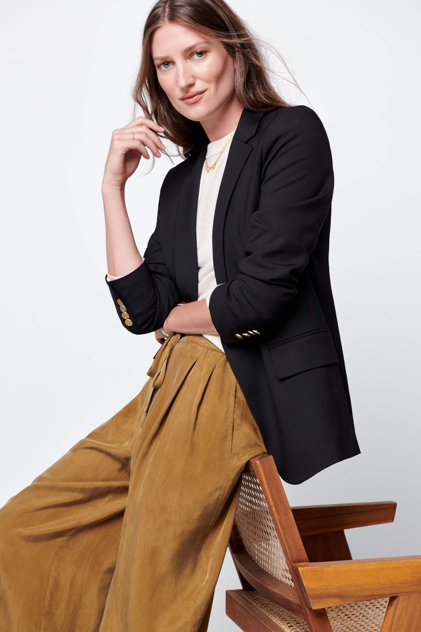 Stitch Fix women's normcore outfit on model wearing black blazer, white top and brown pleated pants.