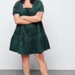 Stitch Fix women’s model in dark academia aesthetic outfit featuring a hunter green babydoll dress and black lace-up combat boots.
