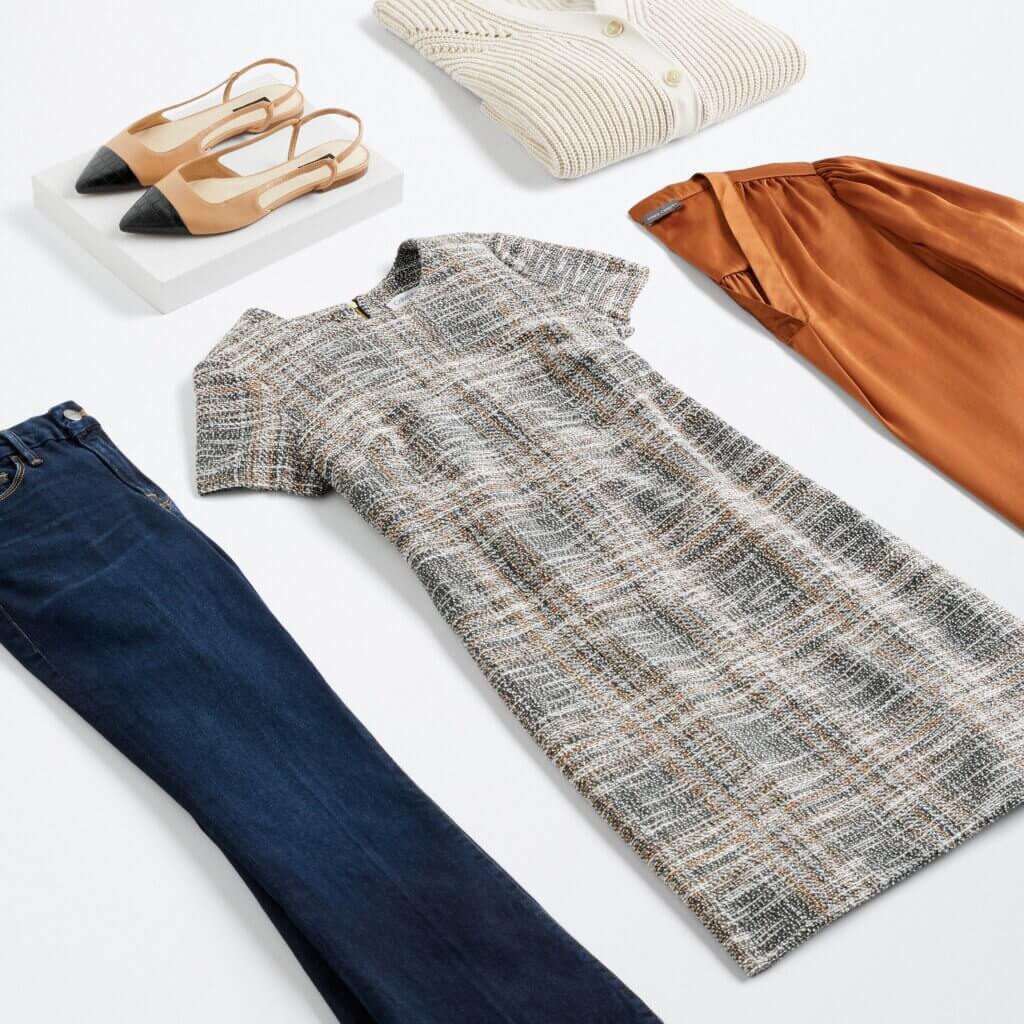 Stitch Fix women’s business attire outfit with plaid sheath dress, orange blouse, dark wash bootcut jeans, off-white cardigan and tan and black slingback flats.