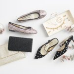 Stitch Fix women’s formal wedding attire outfit accessories with flats, pearl mule slides and clutches next to gold jewelry on a tray.