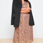 Stitch Fix model wearing women’s plus size formal wedding attire outfit with blush textured dress, black blazer and heels.