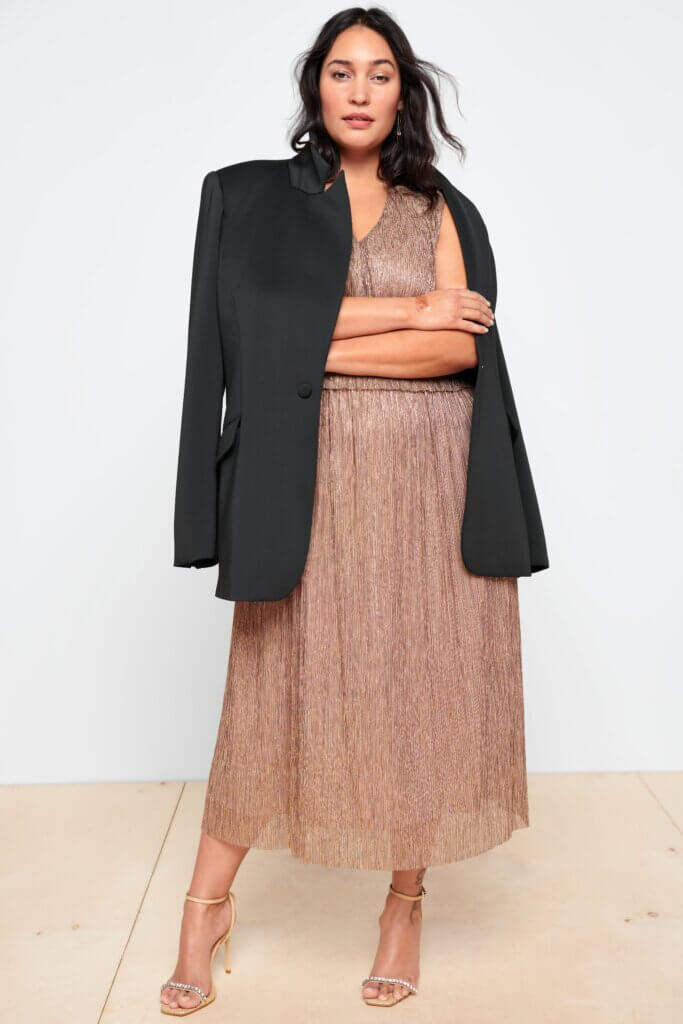 Stitch Fix model wearing women’s plus size formal wedding attire outfit with blush textured dress, black blazer and heels.