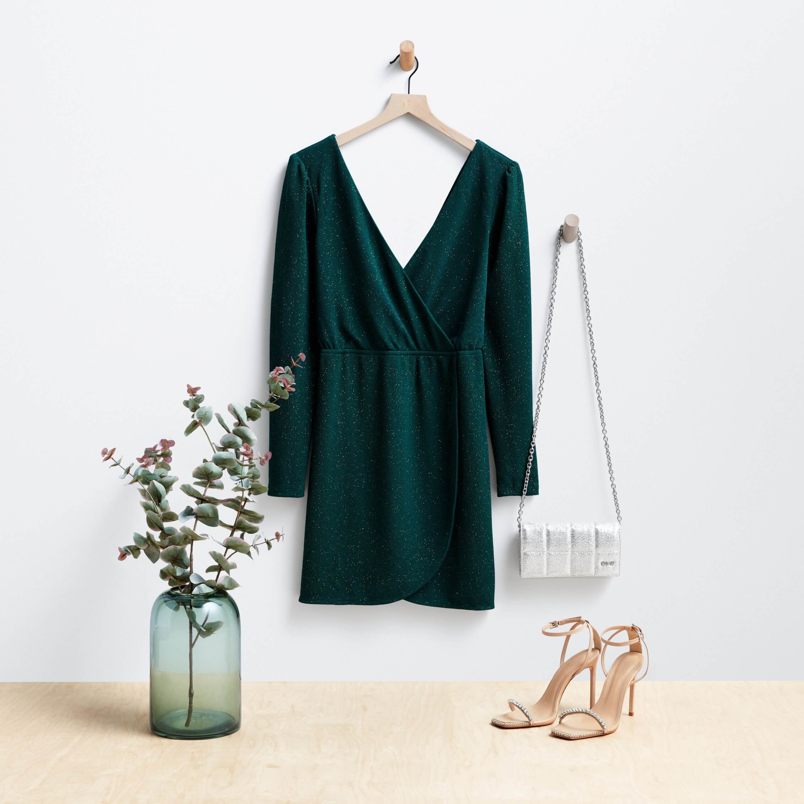 Stitch Fix women's outfit featuring emerald green dress and white clutch hanging on wooden pegs next to nude strappy heels.