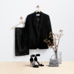 Stitch Fix women’s black-tie wedding attire outfit with black sequin pants, top and velvet blazer on hanger next to heels, handbag and flowers.