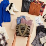 Stitch Fix women’s laydown featuring folded sweaters and jeans in Stitch Fix delivery box next to cream and plaid shackets, mustard purse, cobalt blue balloon sleeve sweater, white booties, black, orange and red plaid button-down shirts, loafers, mauve joggers and black skirts.