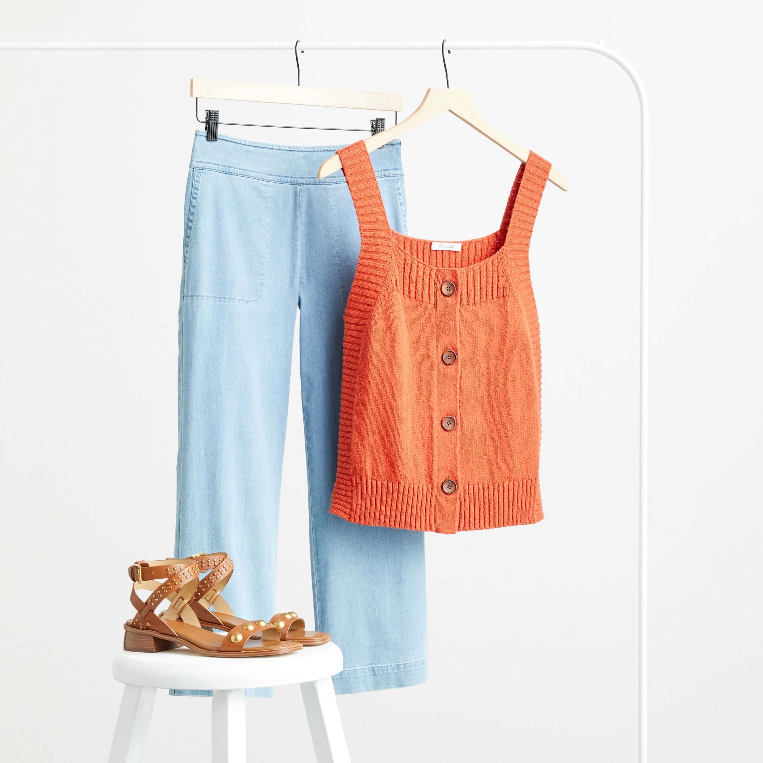 Stitch Fix women’s cropped wide-leg jeans with orange button front tank top and brown sandals on a white stool.