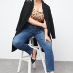 Stitch Fix Women’s model wearing a straight-leg jeans outfit with a polka dot top, black blazer and black pumps.