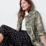 Stitch Fix Women’s model wearing a grunge outfit with midi skirt, turtleneck, camo jacket and black boots.