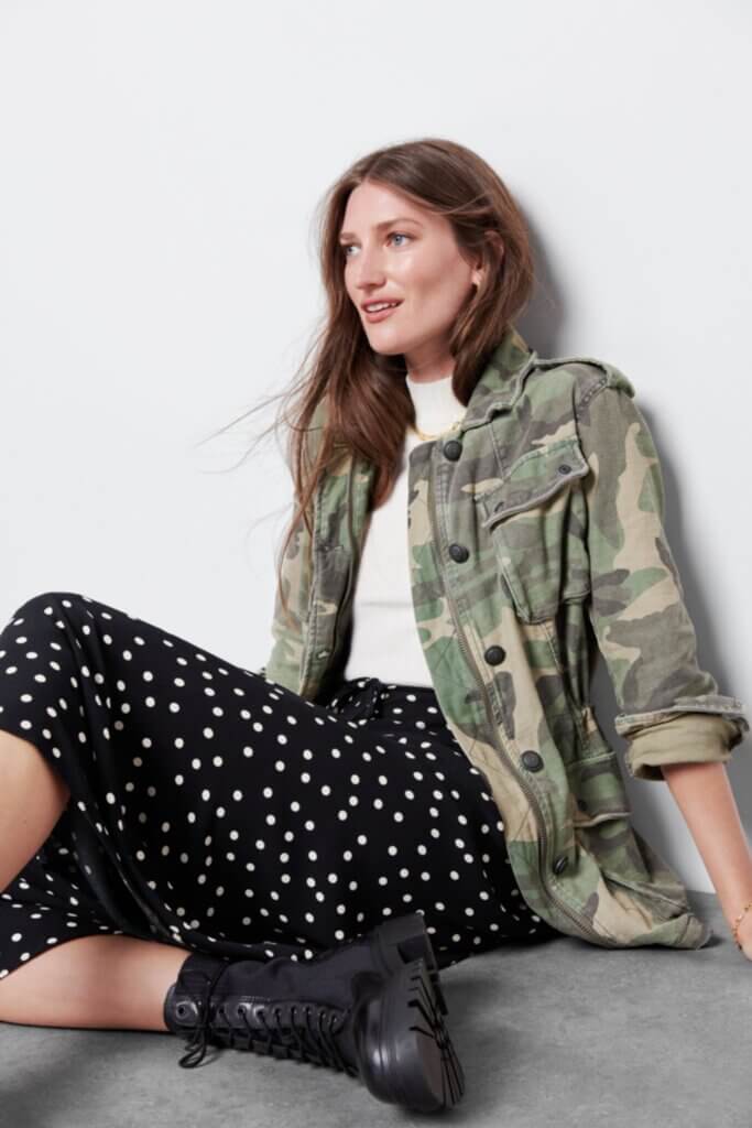 Stitch Fix Women’s model wearing a grunge outfit with midi skirt, turtleneck, camo jacket and black boots.
