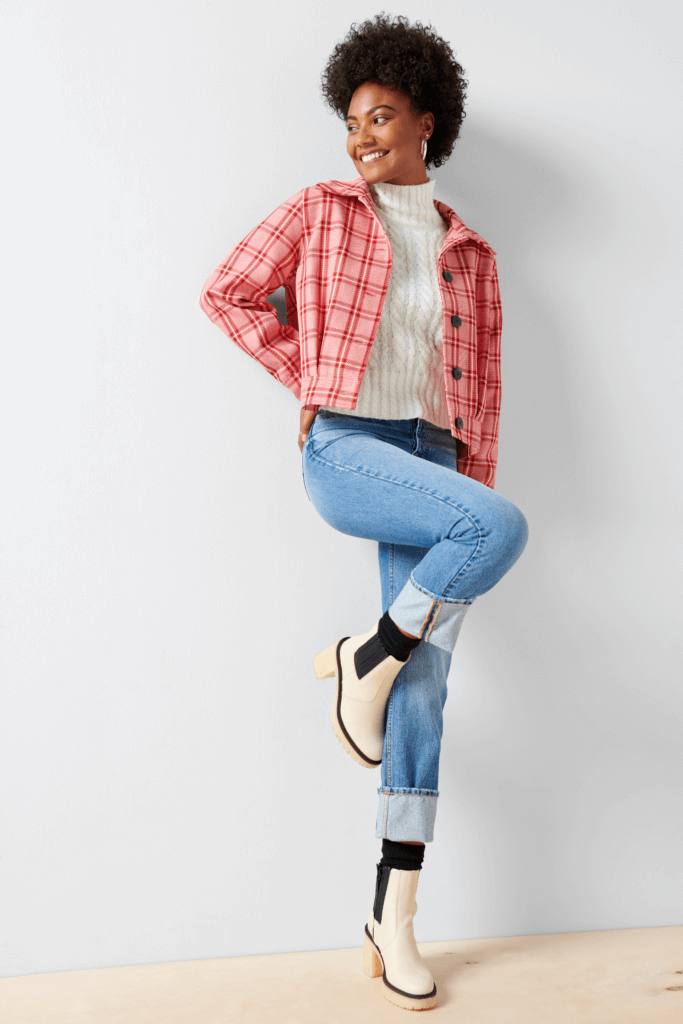 Stitch Fix Women’s model wearing a pumpkin patch outfit with a white turtleneck, jeans, pink plaid jacket and white boots.