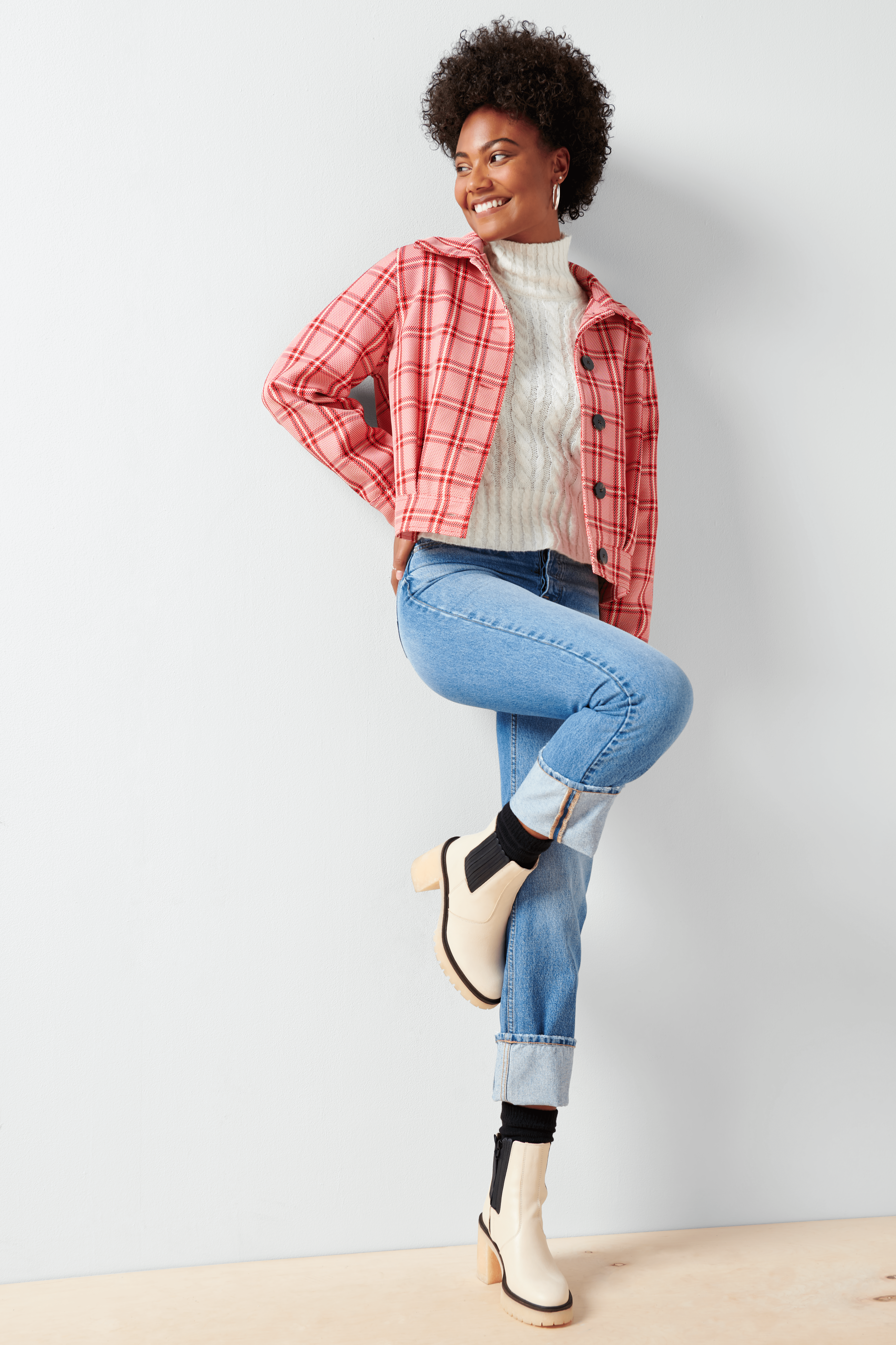 Stitch Fix Women’s model wearing a pumpkin patch outfit with a white turtleneck, jeans, pink plaid jacket and white boots.