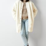 Stitch Fix Women’s model wearing a pumpkin patch outfit with a brown heathers turtleneck, jeans, white coat and grey boots.