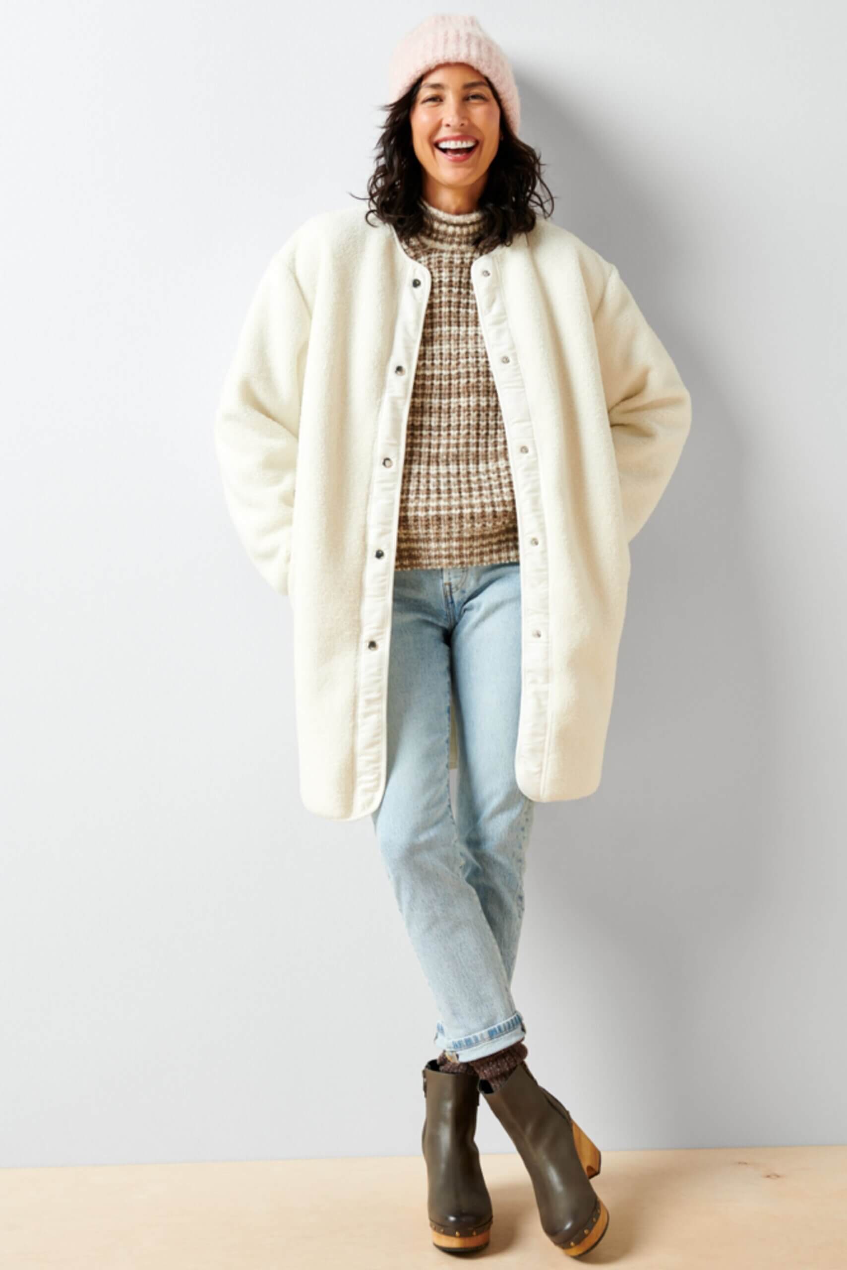 Stitch Fix Women’s model wearing a pumpkin patch outfit with a brown heathers turtleneck, jeans, white coat and grey boots.