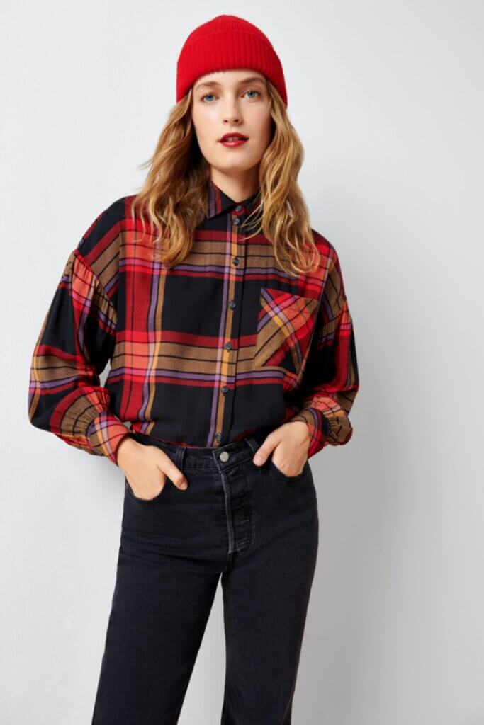 Stitch Fix Women’s model wearing a grunge outfit with black jeans, red and black plaid shirt and red beanie.