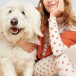 Stitch Fix model wearing a cozy fall aesthetic outfit with matching floral pajamas, beanie, sweater and pink socks with a dog.