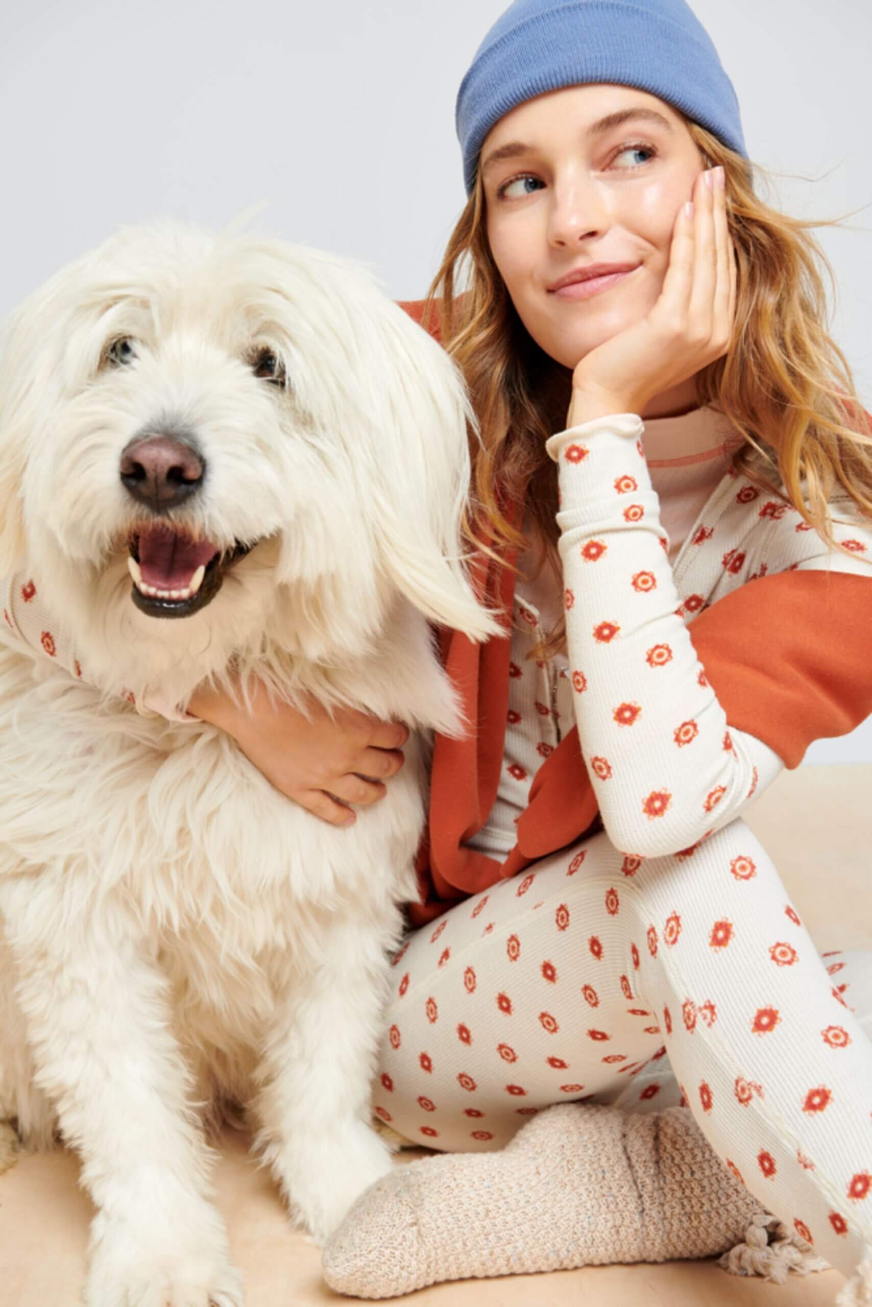 Stitch Fix model wearing a cozy fall aesthetic outfit with matching floral pajamas, beanie, sweater and pink socks with a dog.