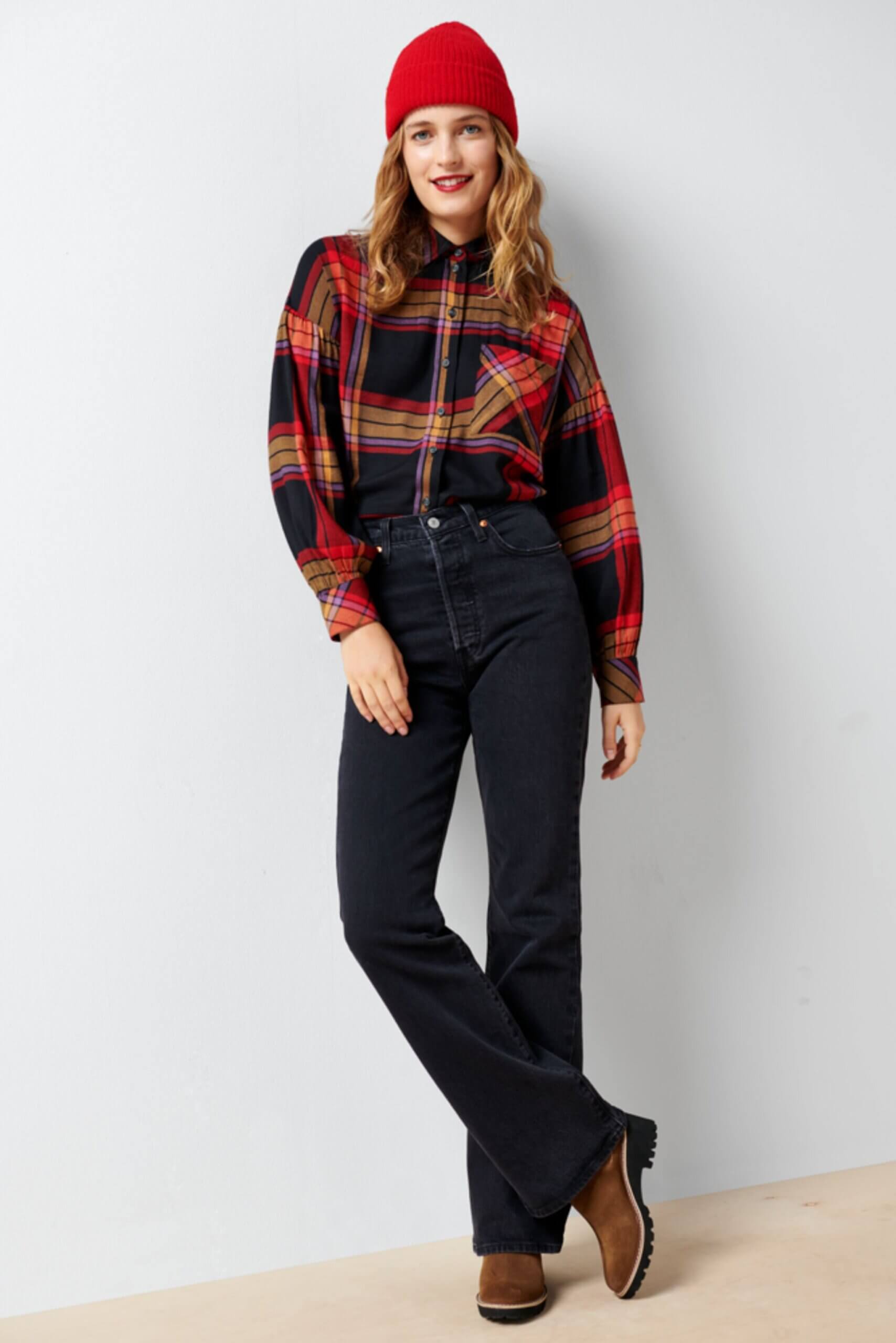 Stitch Fix Women’s model wearing a pumpkin patch outfit with black jeans, plaid blouse, brown boots and red beanie.