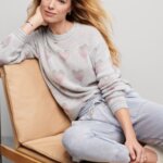 Stitch Fix women’s model wearing a cozy fall aesthetic outfit with grey joggers, grey sweater with pink hearts and white shoes.