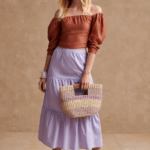 Stitch Fix model wearing women’s cottagecore aesthetic outfit with brown off-the-shoulder blouse, purple tiered midi skirt, rattan bag and tan sandals.