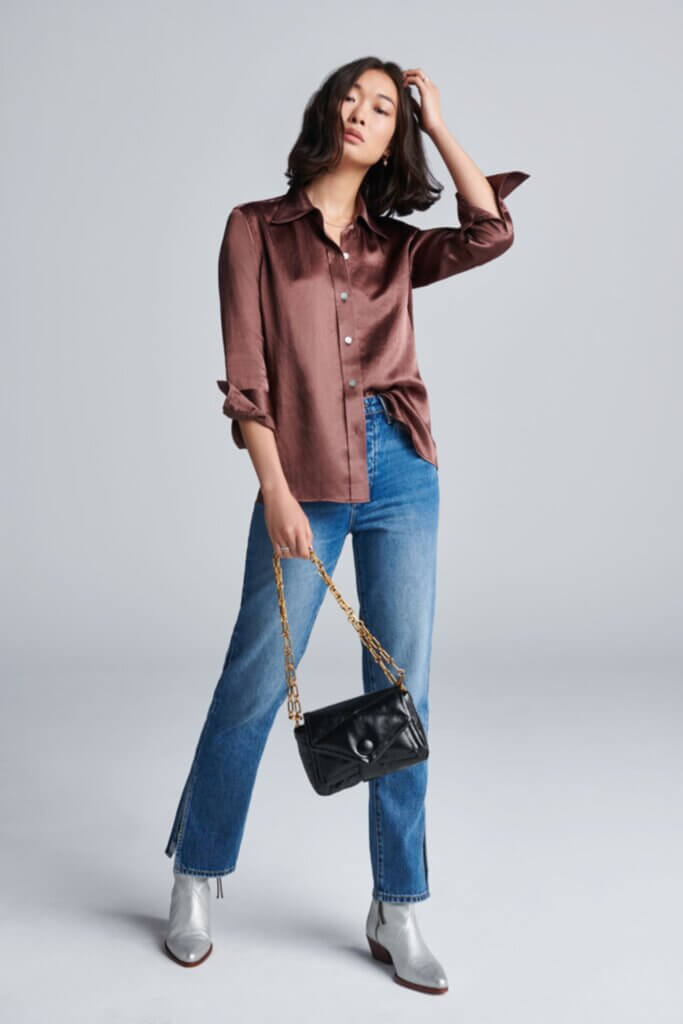 Stitch Fix Women’s model wearing a brown satin button-up, blue jeans, silver booties and black shoulder bag.