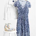 Stitch Fix women’s floral print accessorized navy blue dress for a wedding with pale blue wedges and white denim jacket.