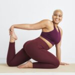 Stitch Fix women's model in stretch pose wearing a yoga outfit featuring matching burgundy sports bra and leggings.