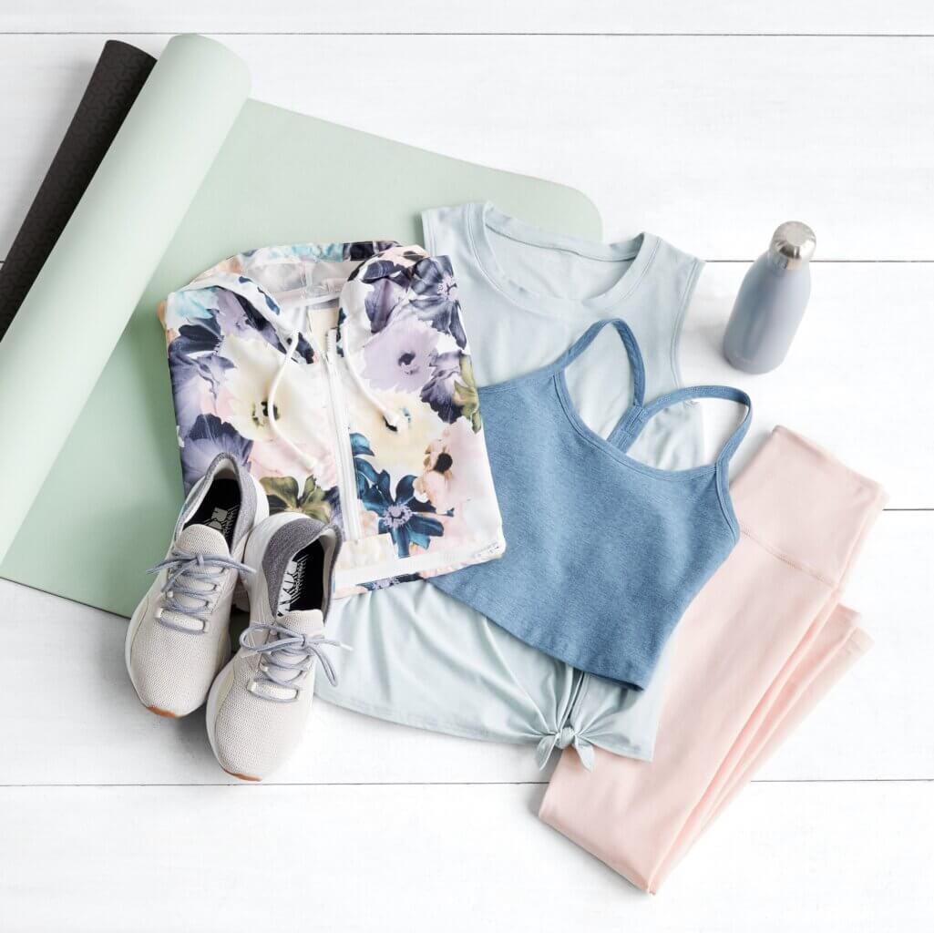 Stitch Fix women’s yoga outfit featuring floral sweatshirt, knotted tank, sports bra, leggings, sneakers and water bottle on yoga mat.