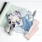 Stitch Fix women’s yoga outfit featuring floral sweatshirt, knotted tank, sports bra, leggings, sneakers and water bottle on yoga mat.