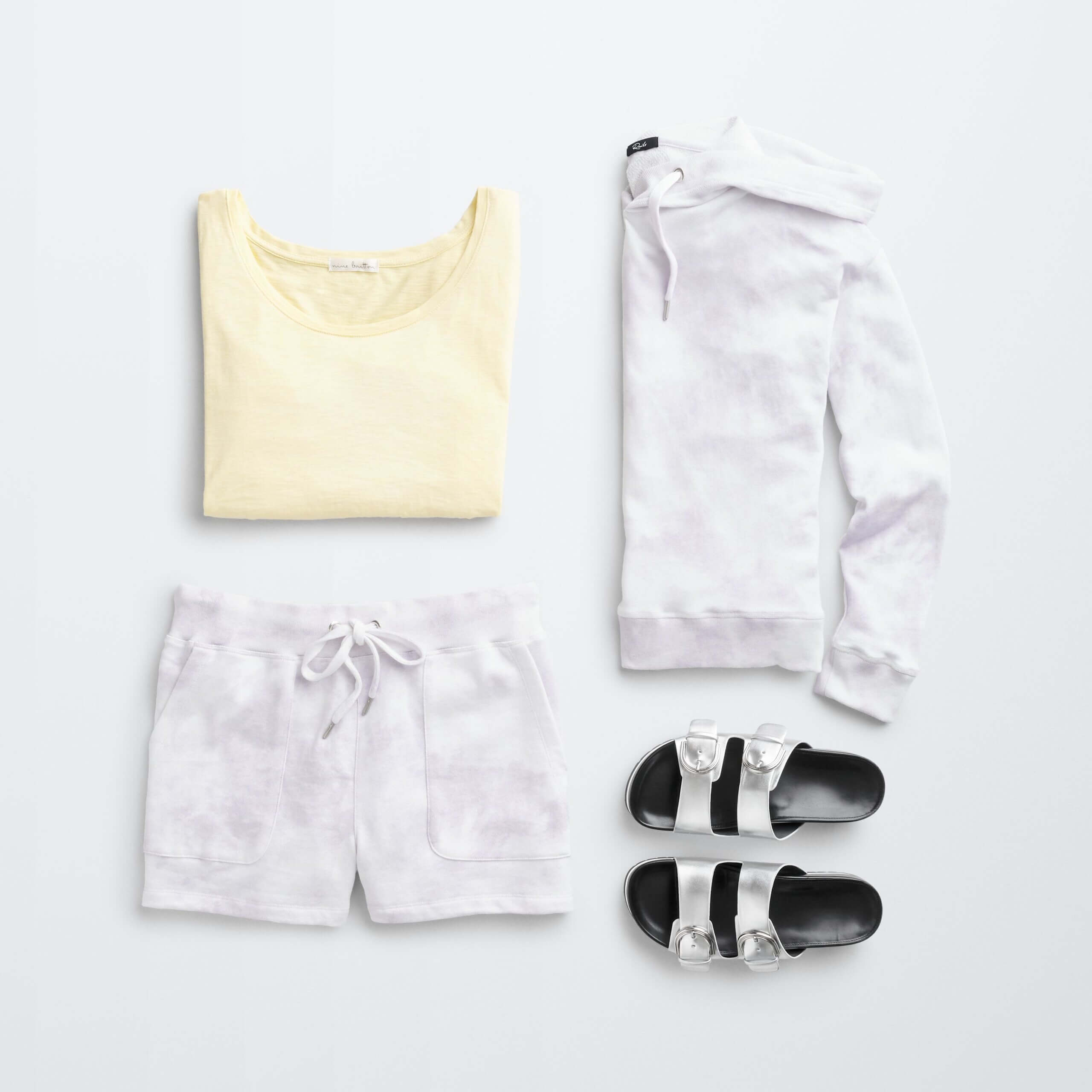 Stitch Fix women’s comfy road trip outfit with yellow tank, silver slide sandals and purple and white tie-dye hoodie and shorts set.